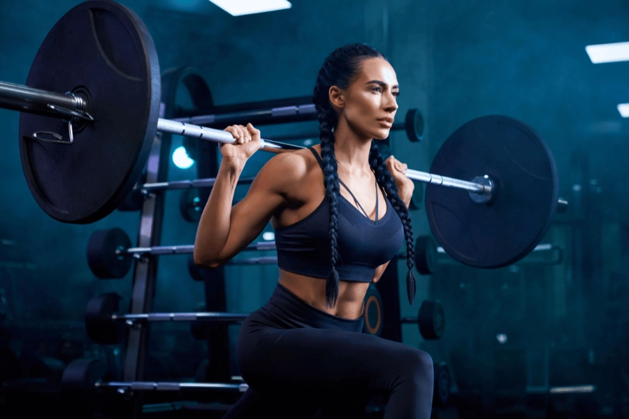 woman doing bulgarian split squats with weights at the gym