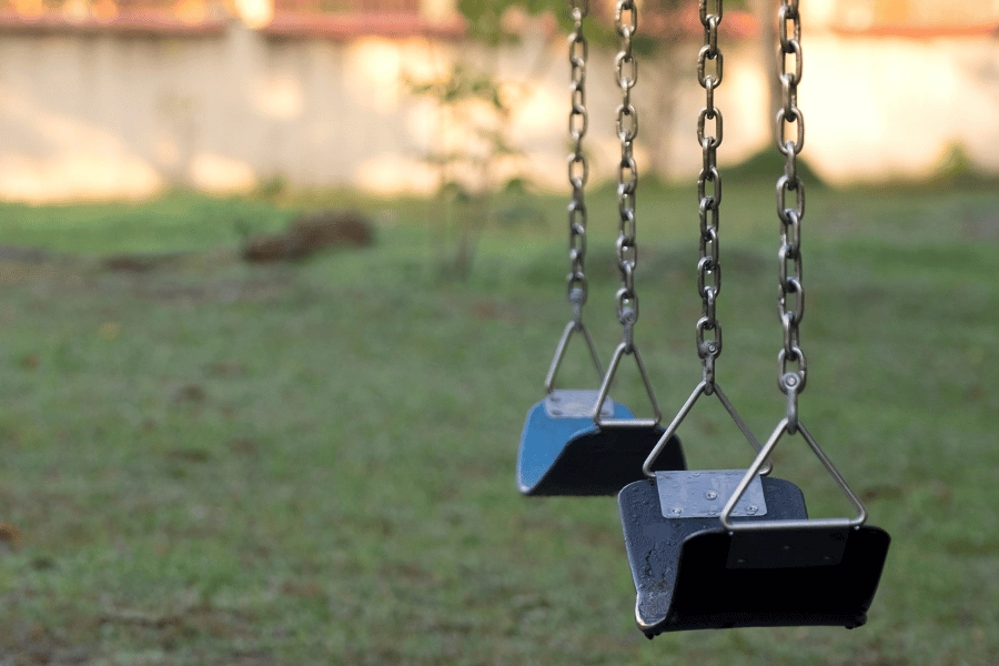 two swings on a playground at a local park 