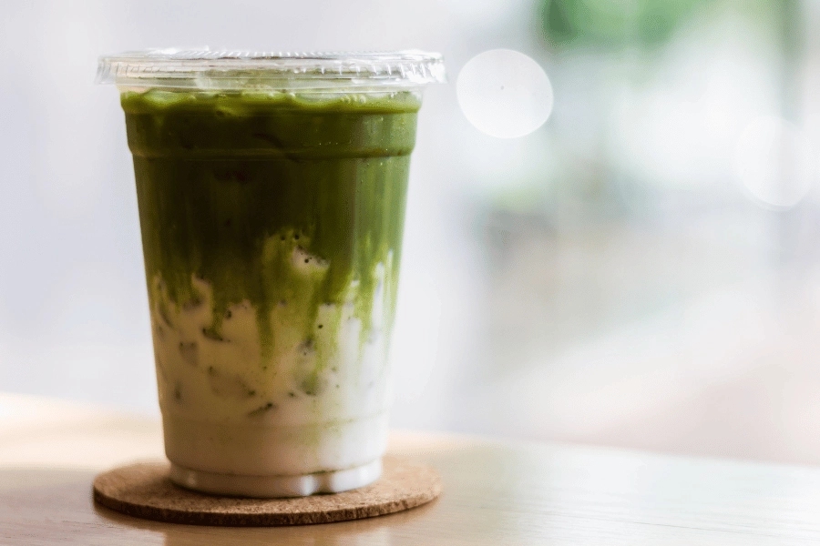 matcha latte in a plastic cup sitting on a coaster