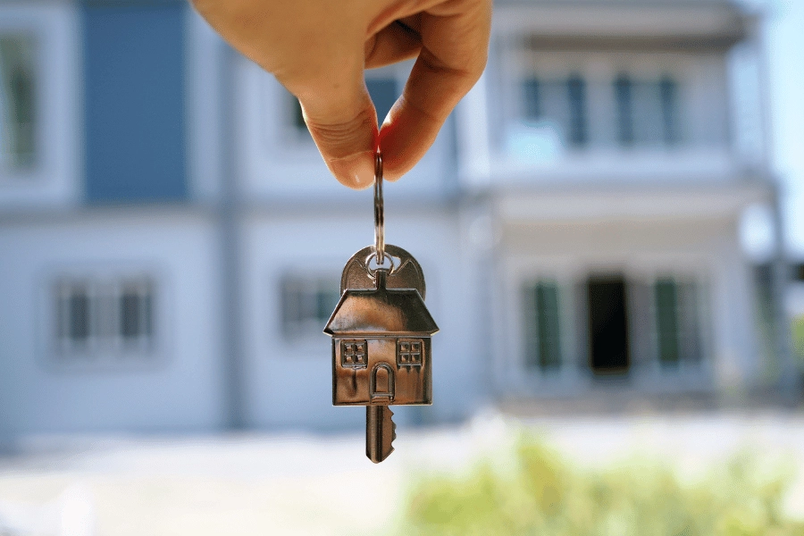 homeowner holding new home keys in front of a house