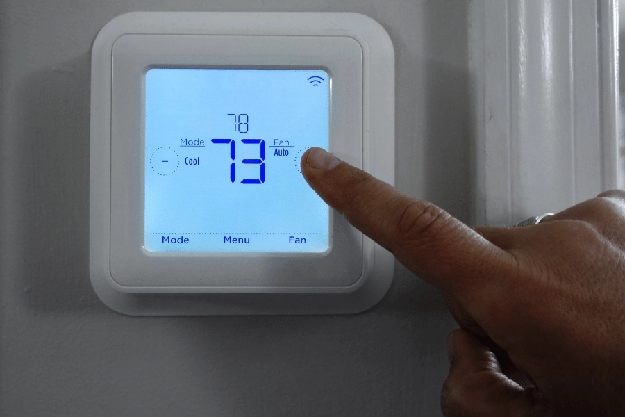 homeowner changing thermostat temperature