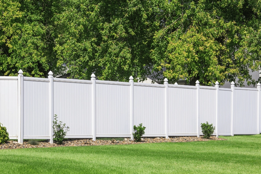 white vinyl fence in a backyard with freshly mowed grass