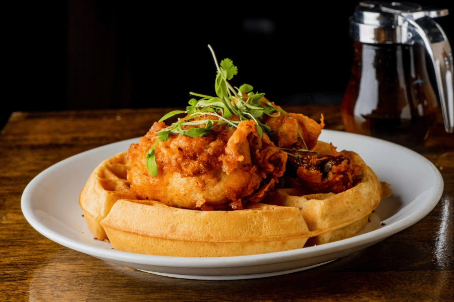 plate of fresh chicken and waffles with maple syrup