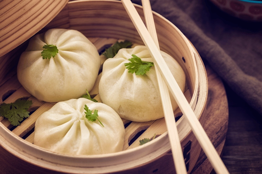 dim sum dumplings with chopsticks topped with garnish