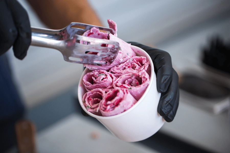 delicious rolled ice cream being placed in a white cup