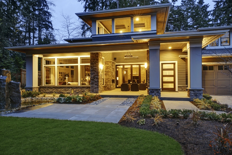 luxurious home with lots of outdoor lighting and maintained landscaping