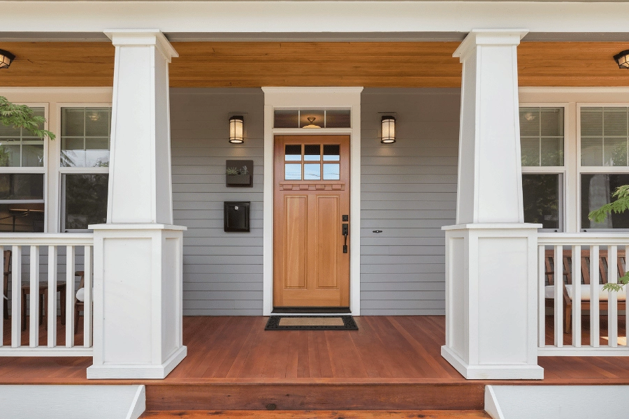 beautiful home front porch with light wood front door and gray siding
