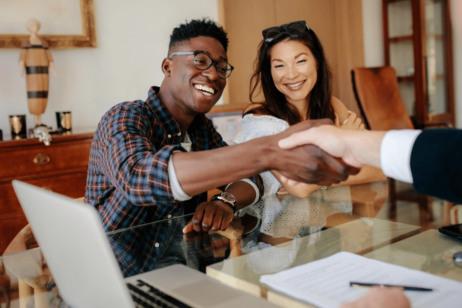 homebuyer shaking hands with a realtor in an office