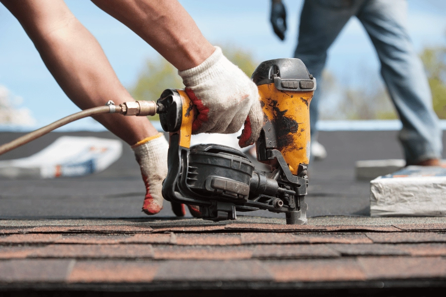 workers replacing a roof and using a nail gun 