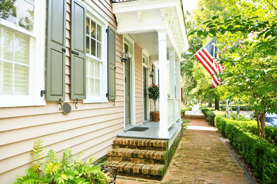 beautiful historic home with American flag flying in the front and green shutters