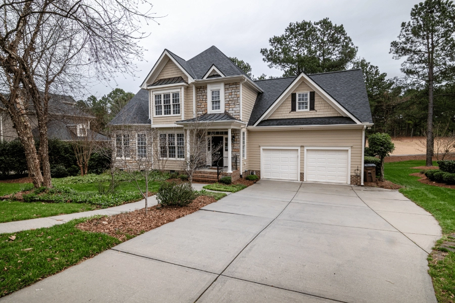 white and brown suburban home with large driveway located on a golf course