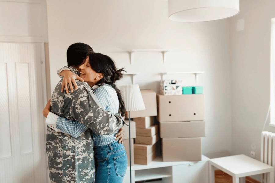 military couple hugging in their new home surrounded by boxes
