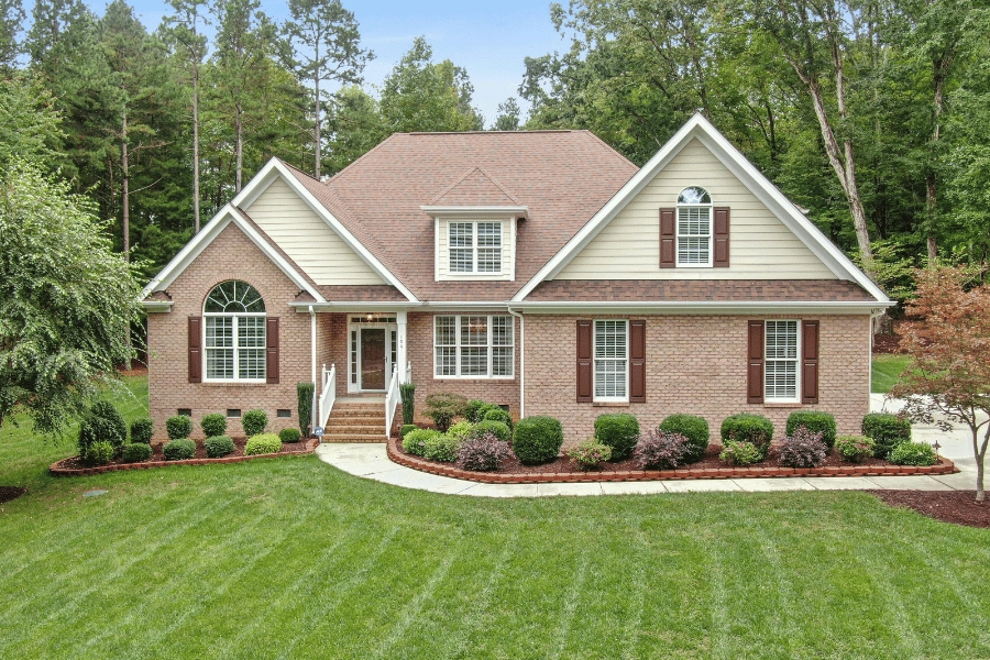 large brick house with freshly mowed lawn brown shutters
