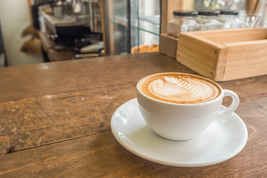 cute latte art in a white mug and saucer on a wood table in a coffee shop