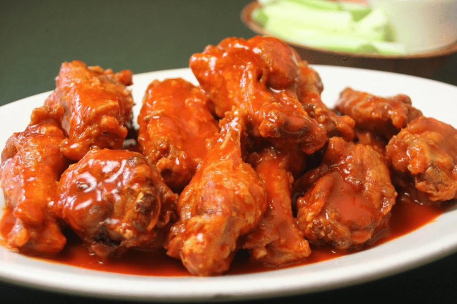 chicken wings on a white plate covered in sauce