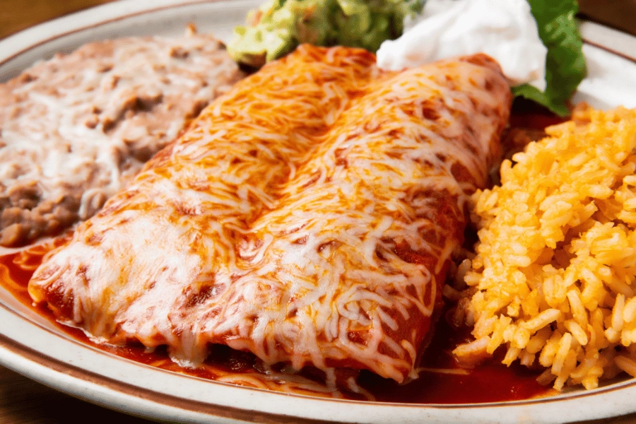 cheesy enchiladas with rice and beans and red sauce