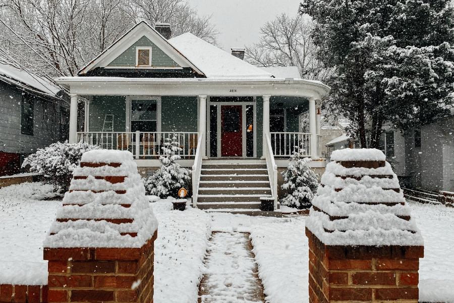 cute green house with front porch on a snowy day