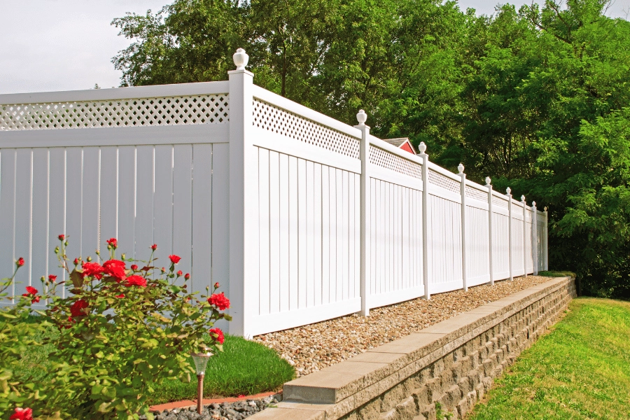 white picket fence surrounded by red flowers and rocks