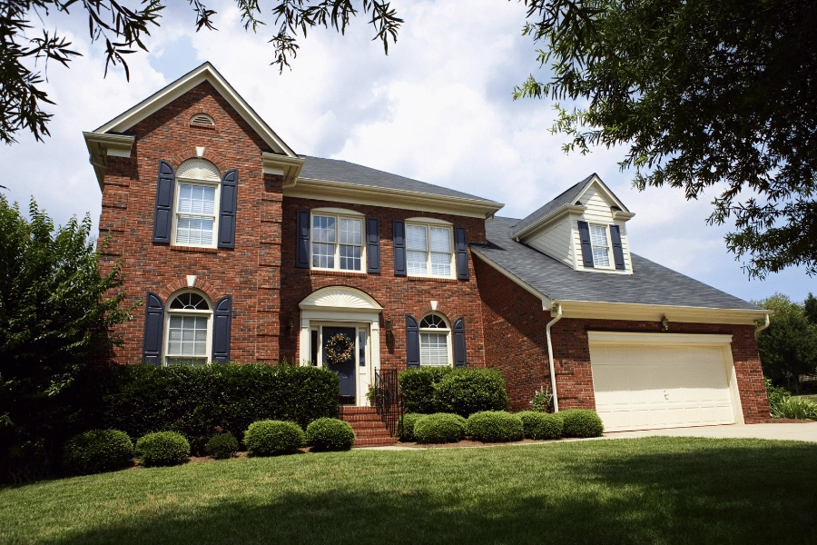traditional brick single-family home with two car garage and dark blue shutters