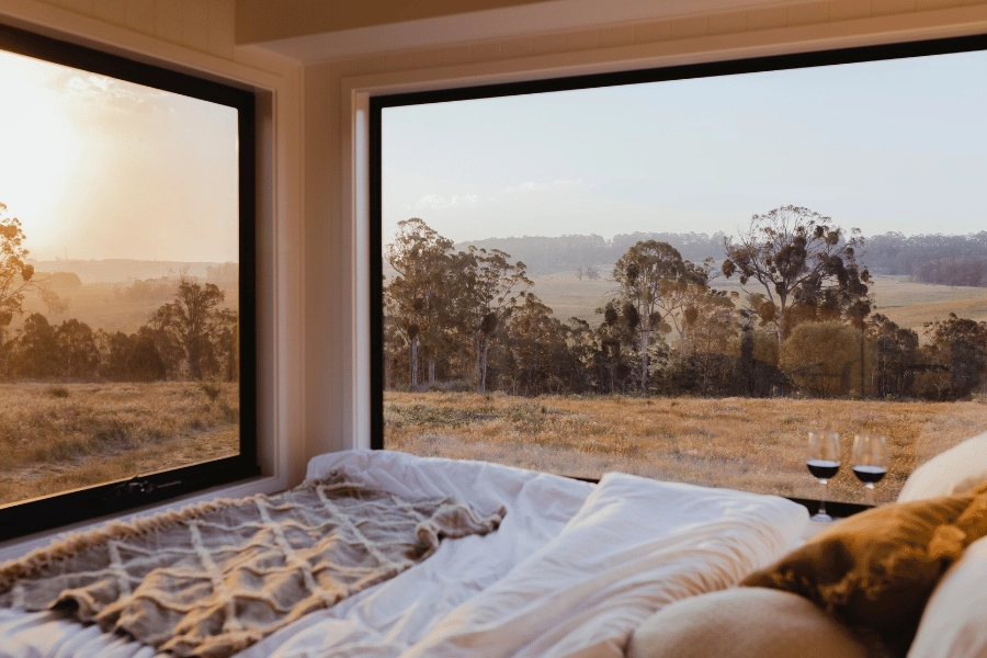 bedroom in tiny home with large windows and amazing view of nature