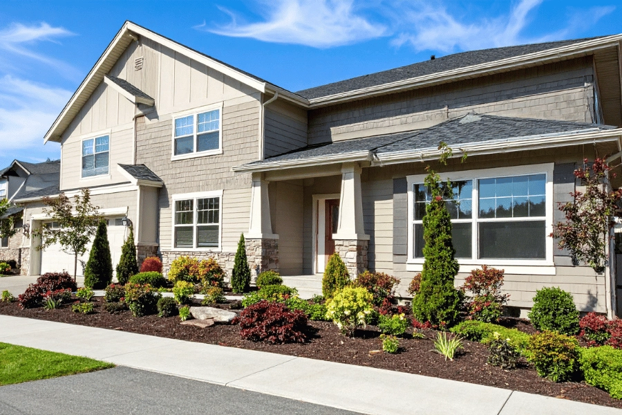 beautiful home with front porch, garage, large windows, and plants in the front yard