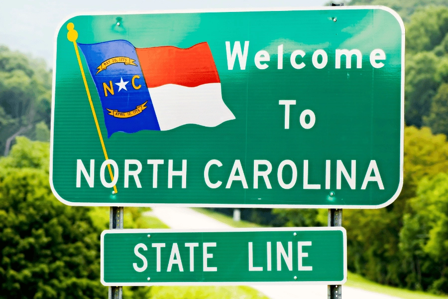 North Carolina state line green road sign with state flag 