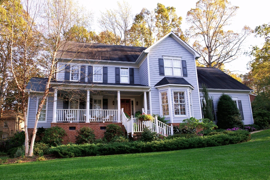 single-family home with front porch, blue shutters, and lush and green front yard