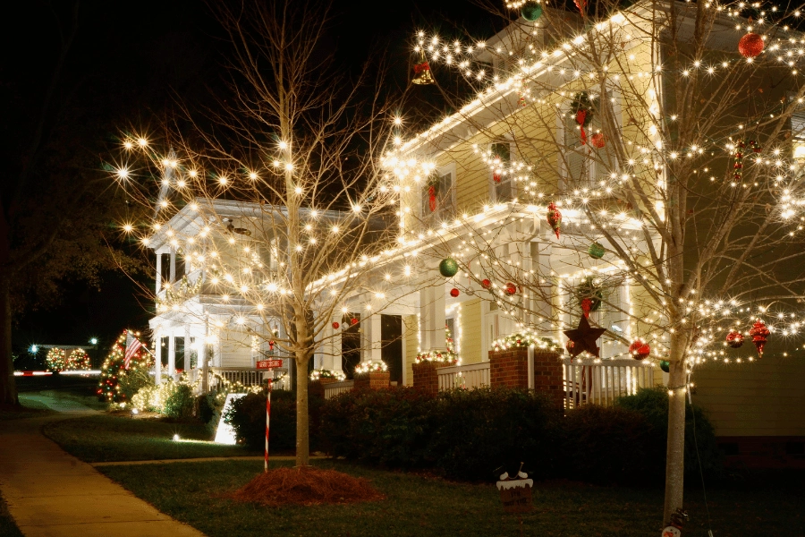 Beautiful home Christmas light display with bright lights and ornaments in the tree