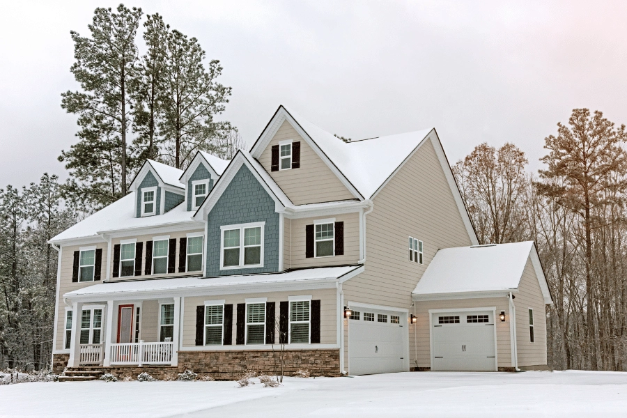 large single-family home in the snow during the winter with front porch and big driveway