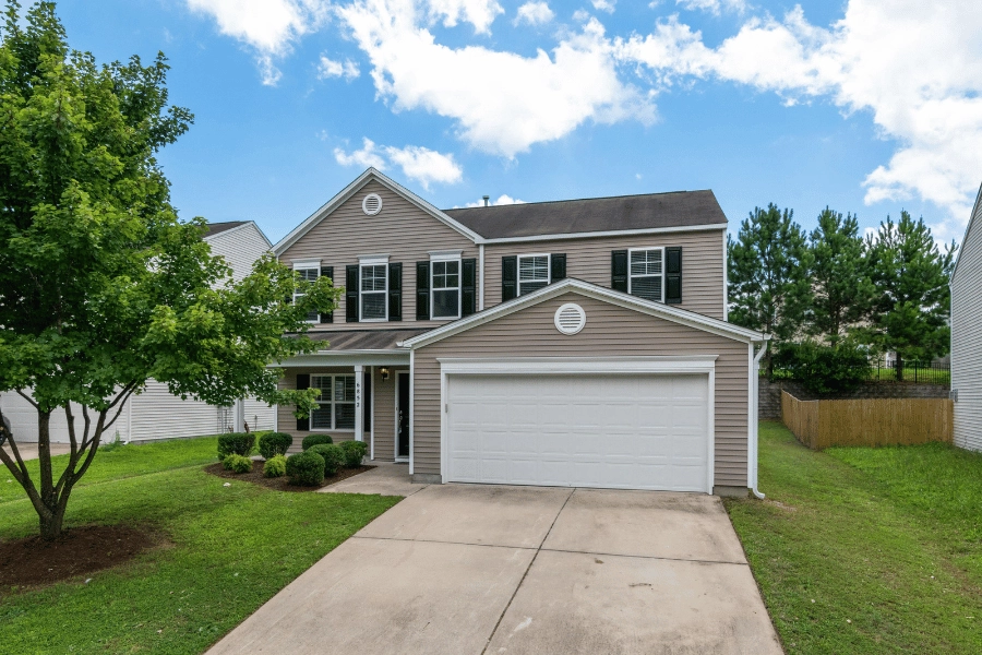 single-family home with two car garage and large tree in the front yard