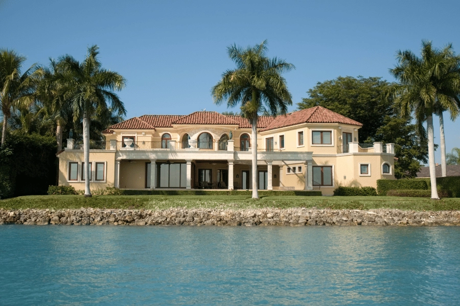 large waterfront home surrounded by palm trees