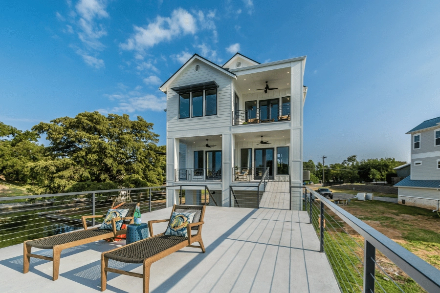 beautiful home on a lake with lots of windows and lounge chairs