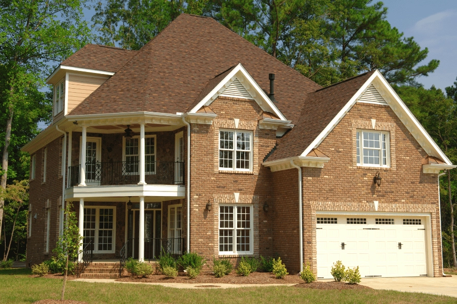 large brick home with two front porches and well-maintained front yard