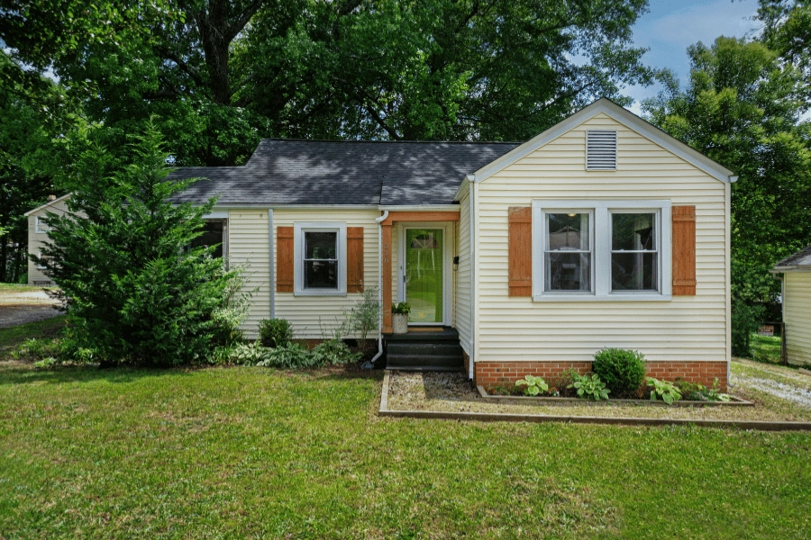 older suburban home in a quiet neighborhood with wood shutters and well-maintained front yard
