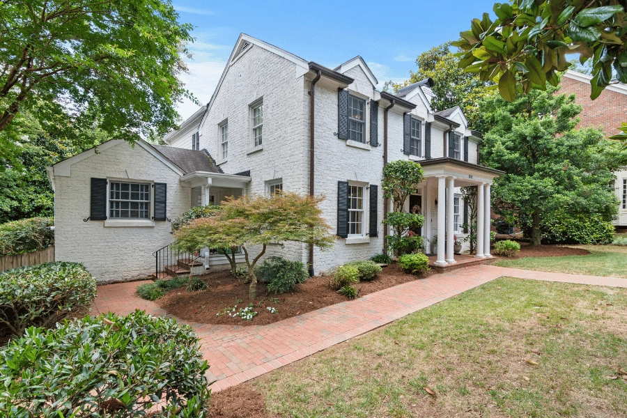 white brick older home with black gutters and brick walking path