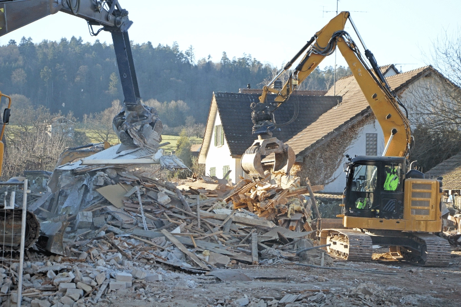 builders and workers tearing down a home with an excavator