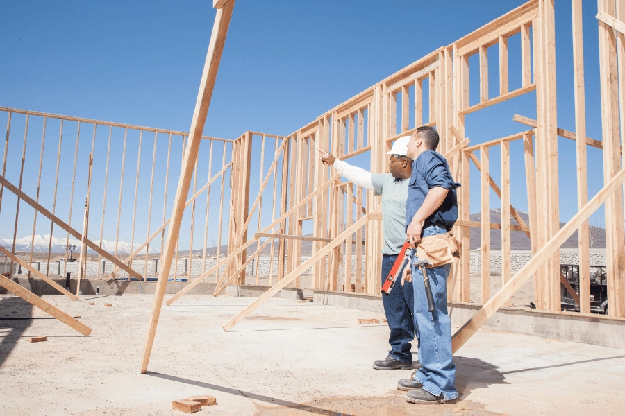 builders talking and working on a wood frame of a new home