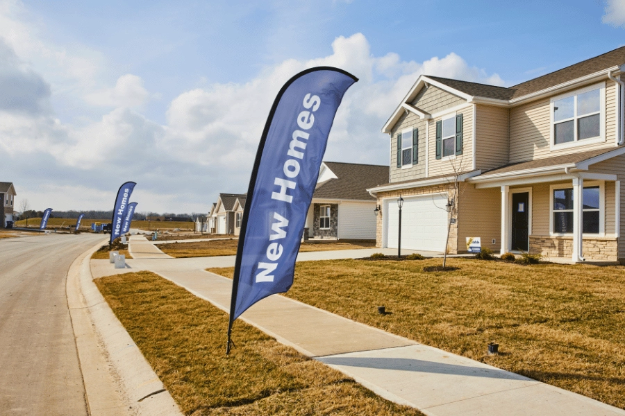 Blue new homes sign in front of new construction homes in suburban neighborhood